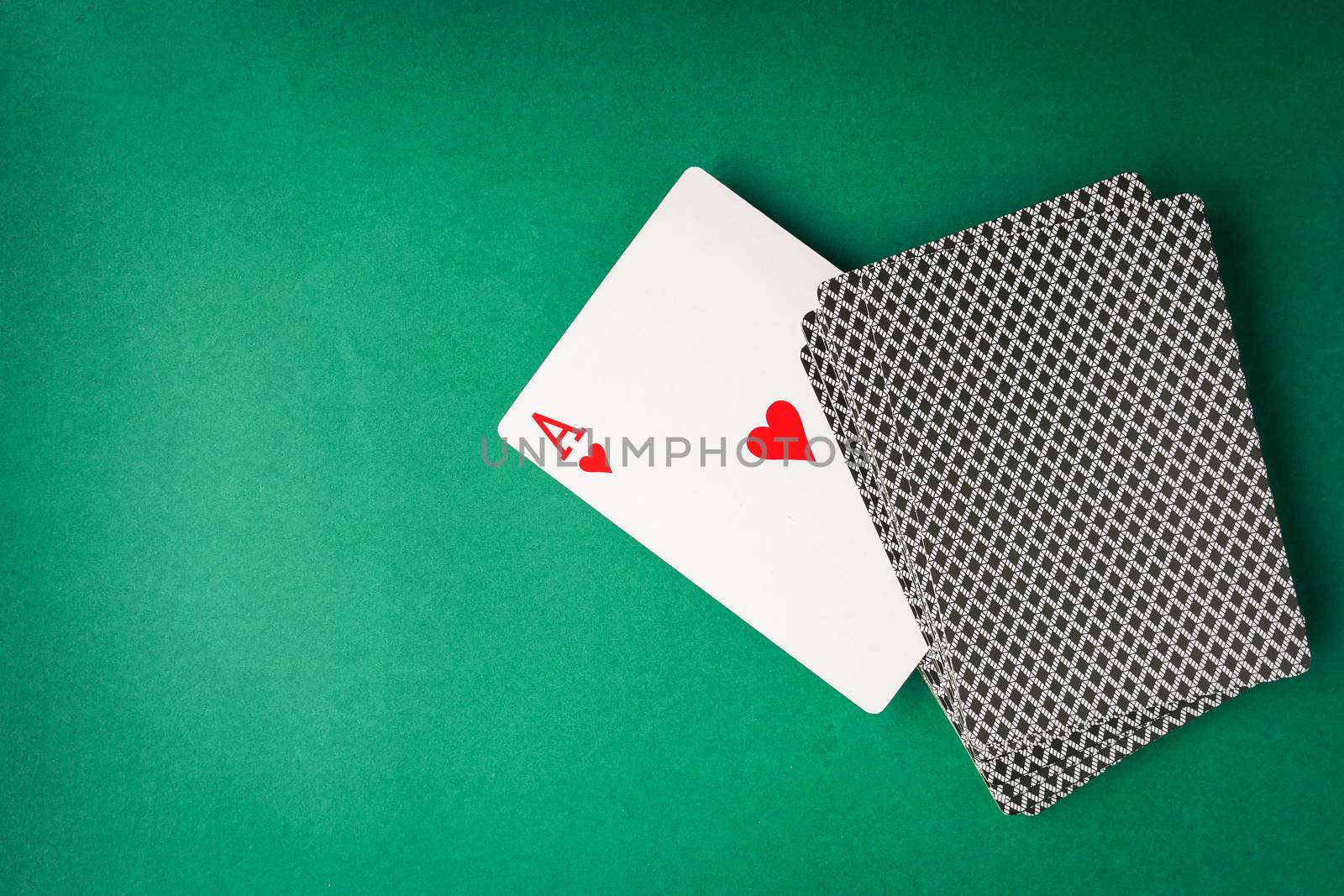 Heart ace with playing cards on green background. Free space for text