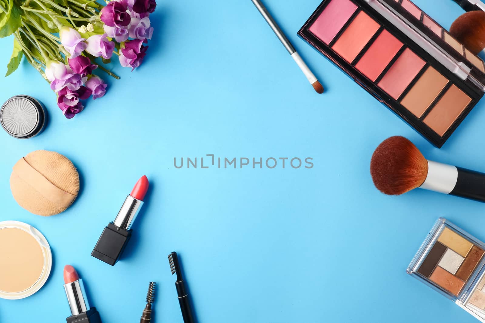 Top view of cosmetics set for makeup on a blue background. Free space for text.