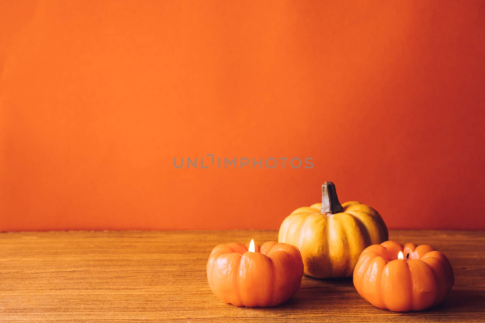 Pumpkins with candlelight on an orange color background. Free space for text