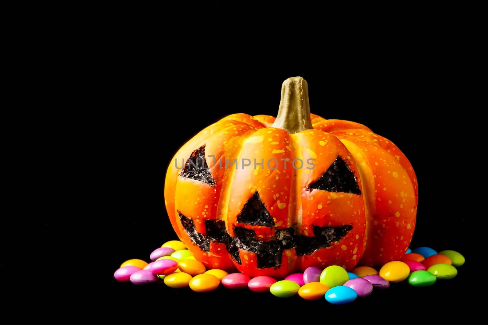 Halloween pumpkin with candies on a black background.