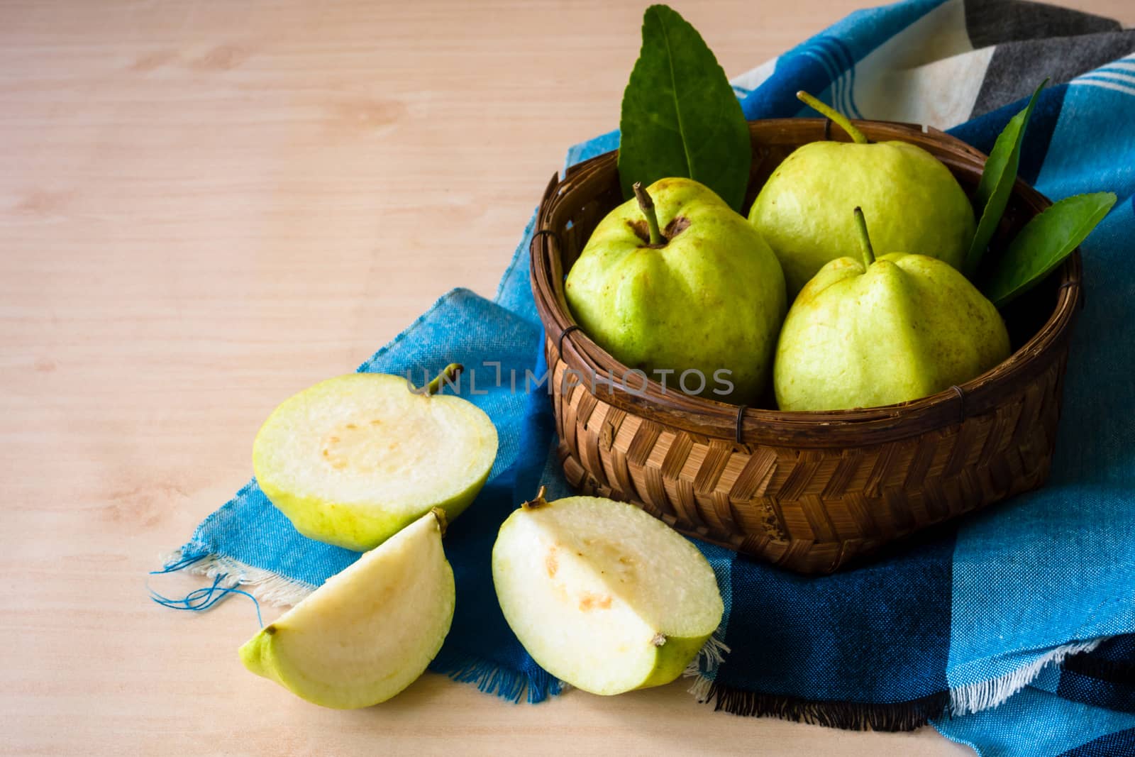 Fresh guava fruit in basket on wooden table background.