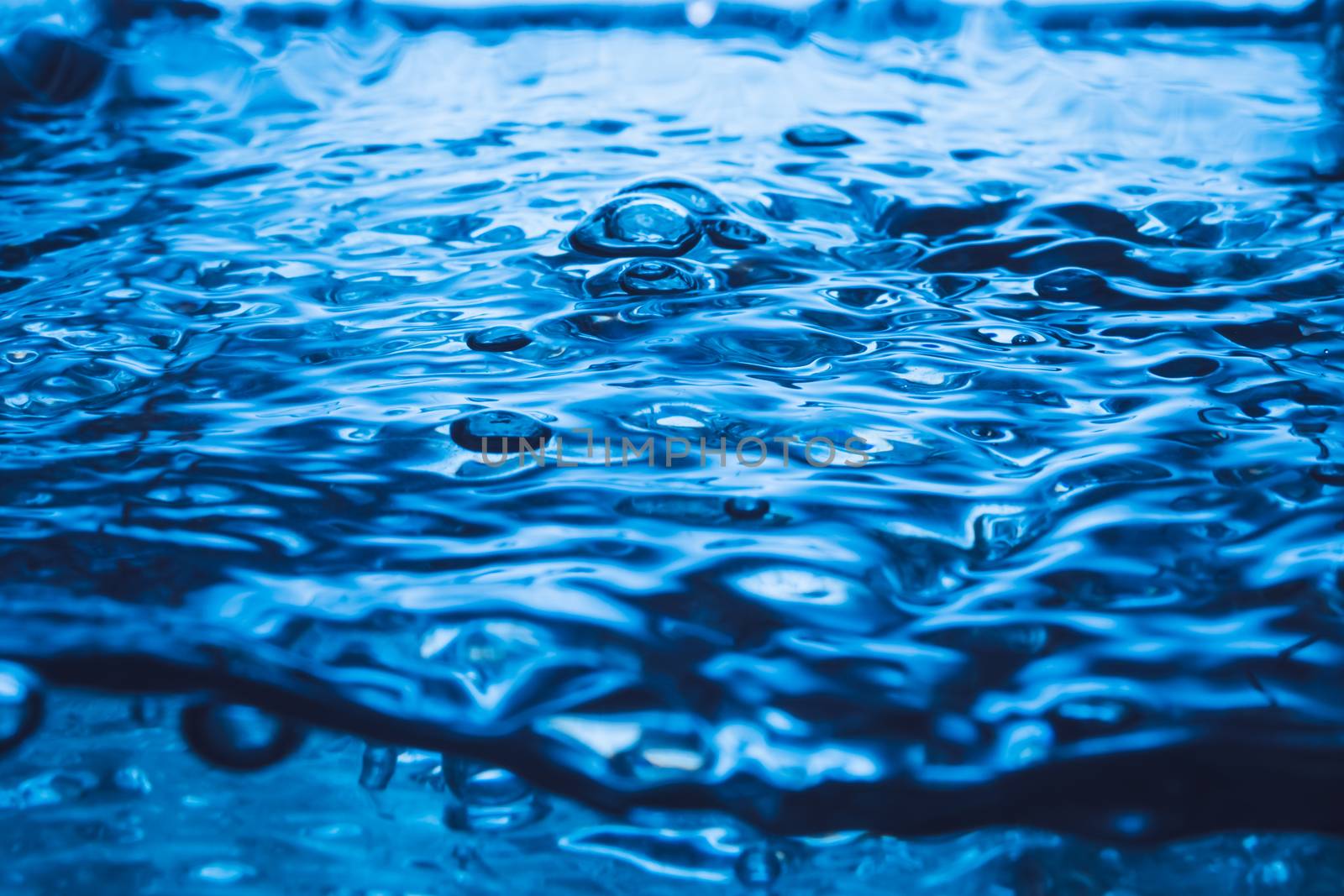 Blue wave and bubbles on water surface background.