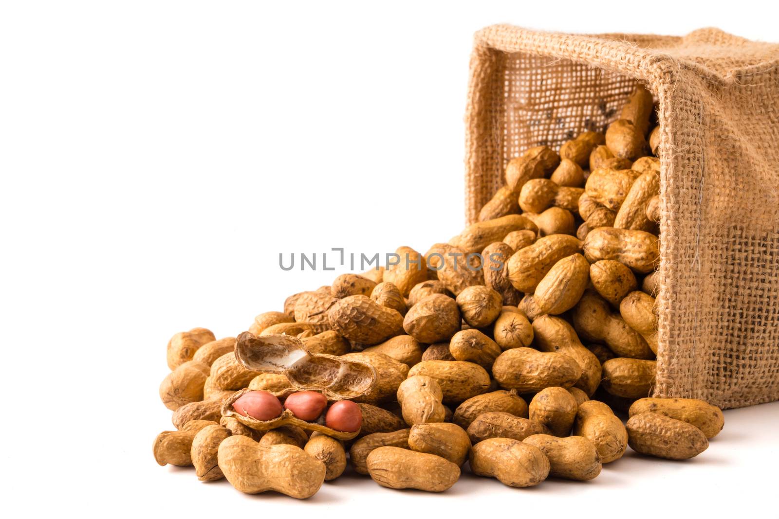 Peanuts in burlap bag on white background.