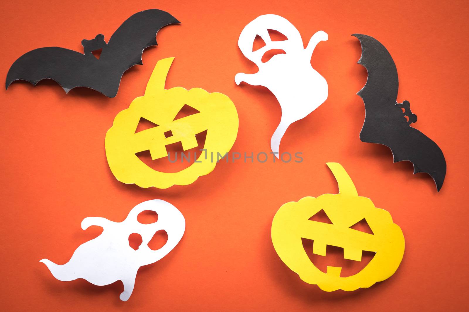Halloween holiday background with pumpkins, ghosts and bats cut paper on orange background.