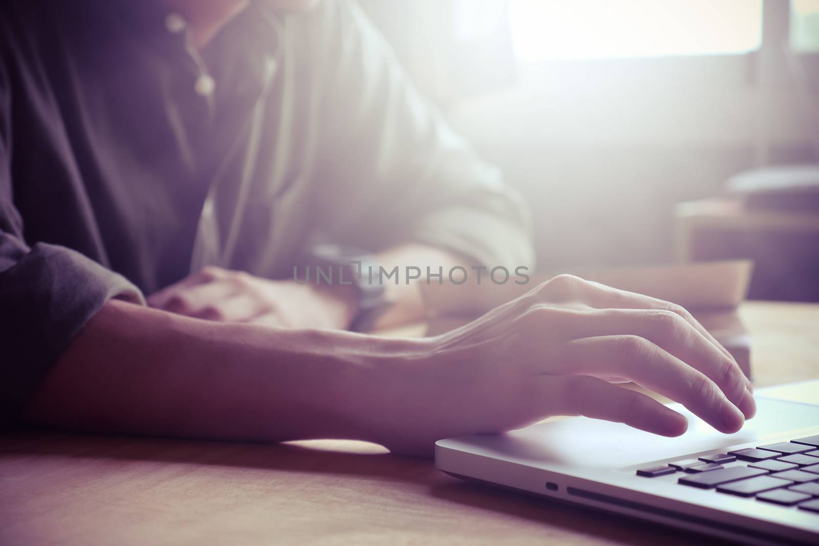 Close up of Male hands using laptop on the table, toned with sunlight