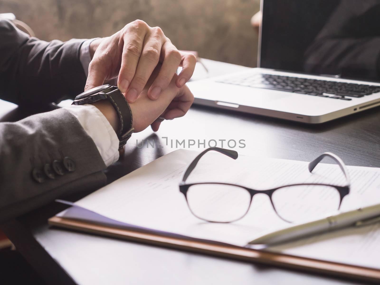 Close up of Businessman working on the desk and checking time on his wrist watch.