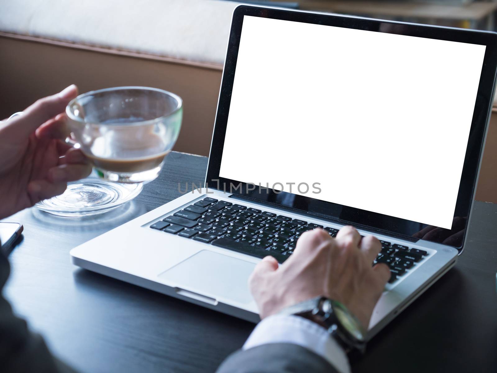 Close up of businessman using a laptop with white screen on the desk.