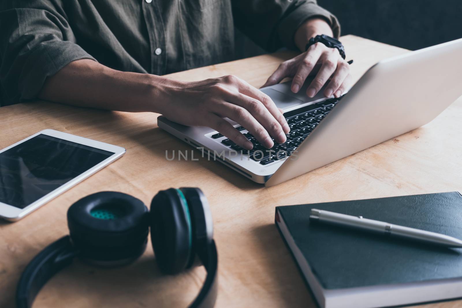 Close up of casual man using laptop on the desk at home.