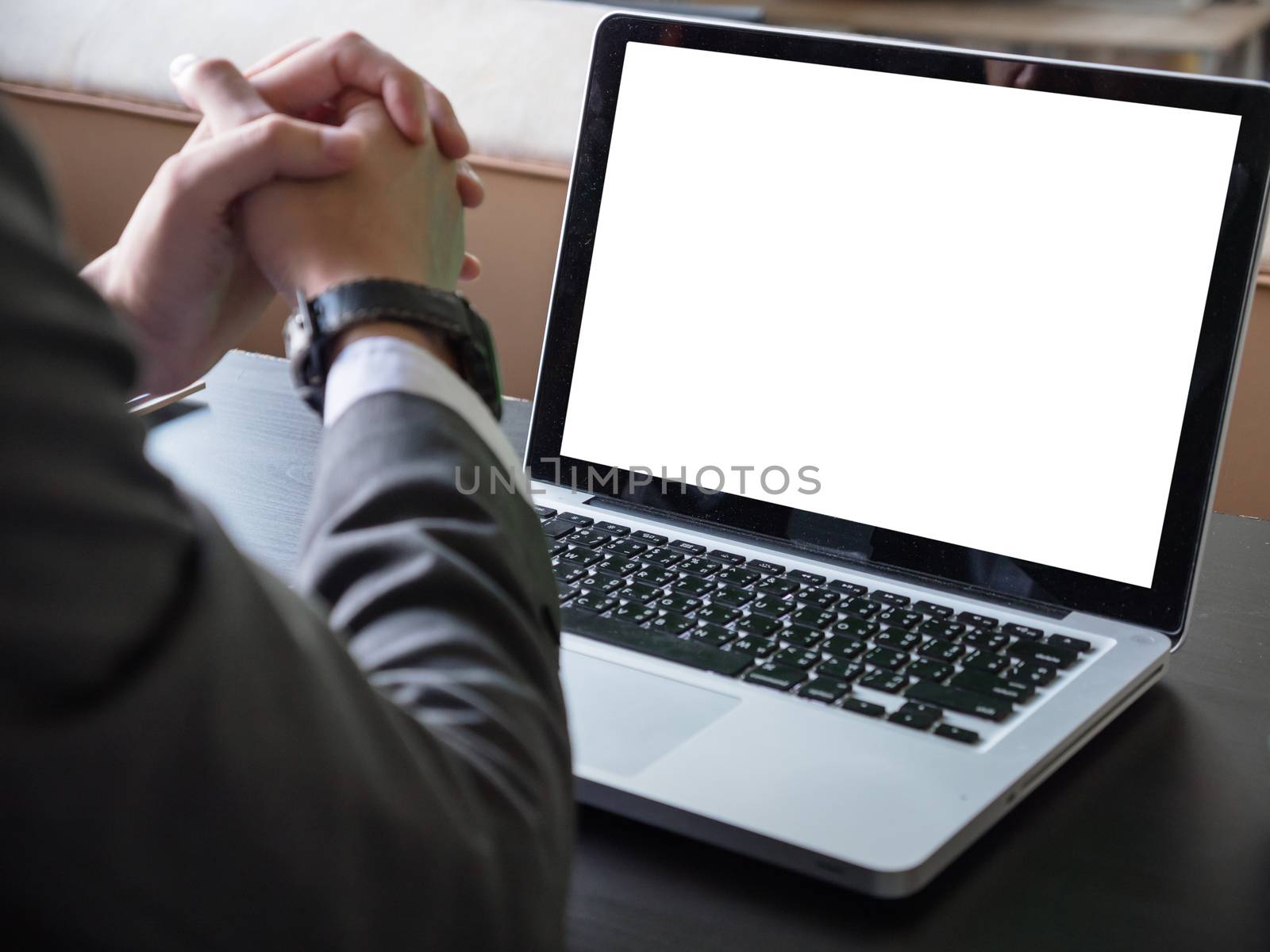 Close up of businessman using a laptop with white screen on the desk.