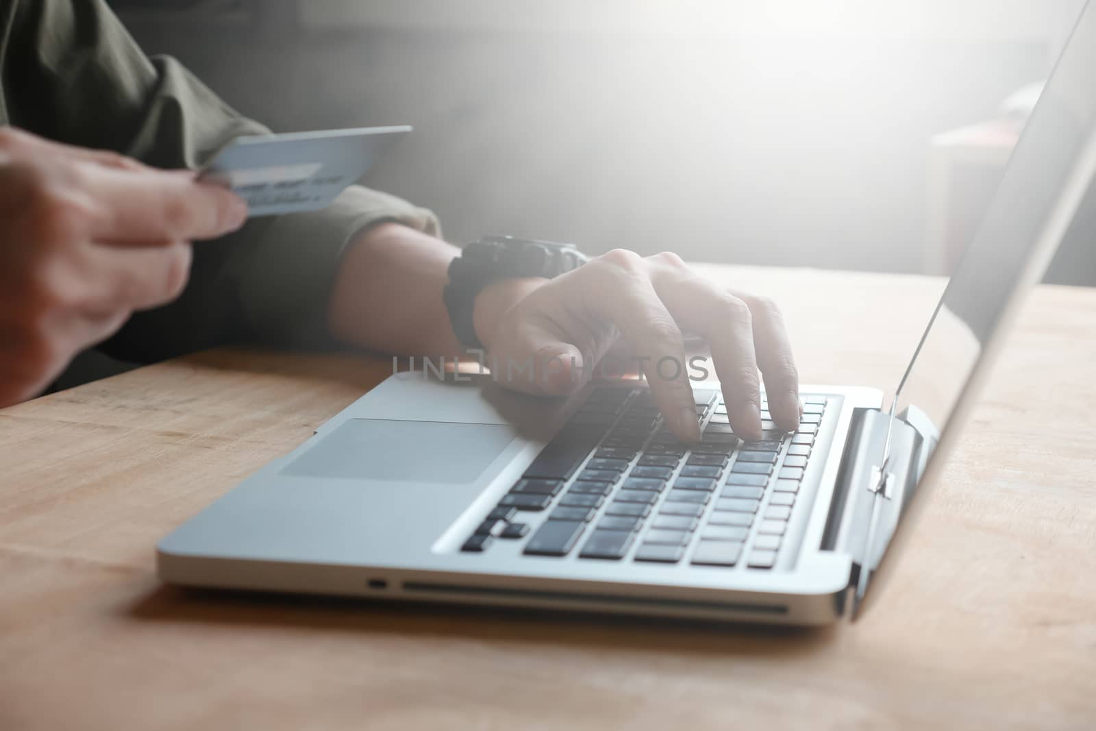 technology, shopping and banking concept - Close up of casual man holding credit card and using laptop on the table, toned with sunlight