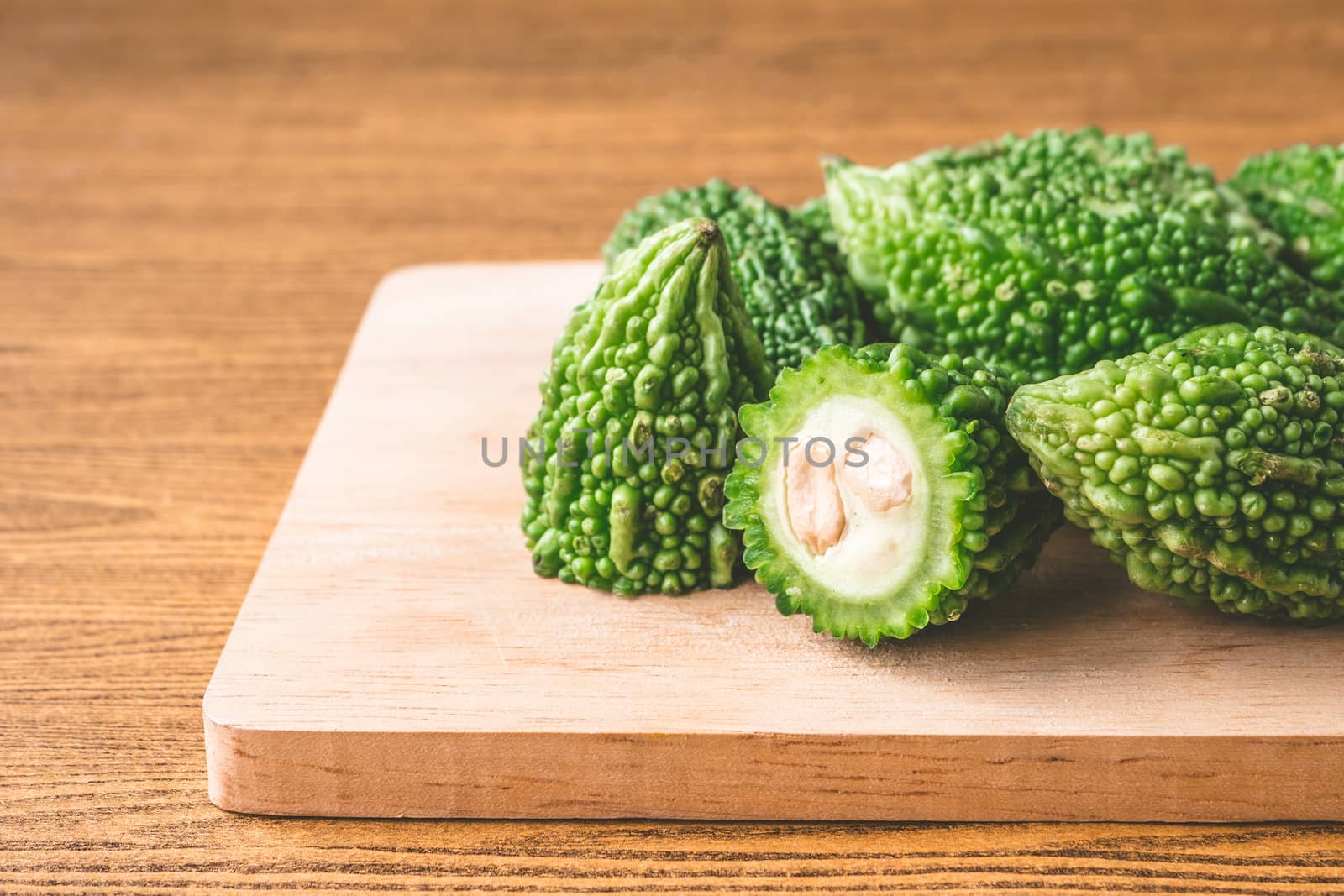 Bitter melon or bitter gourd on wooden tray. Free space for text