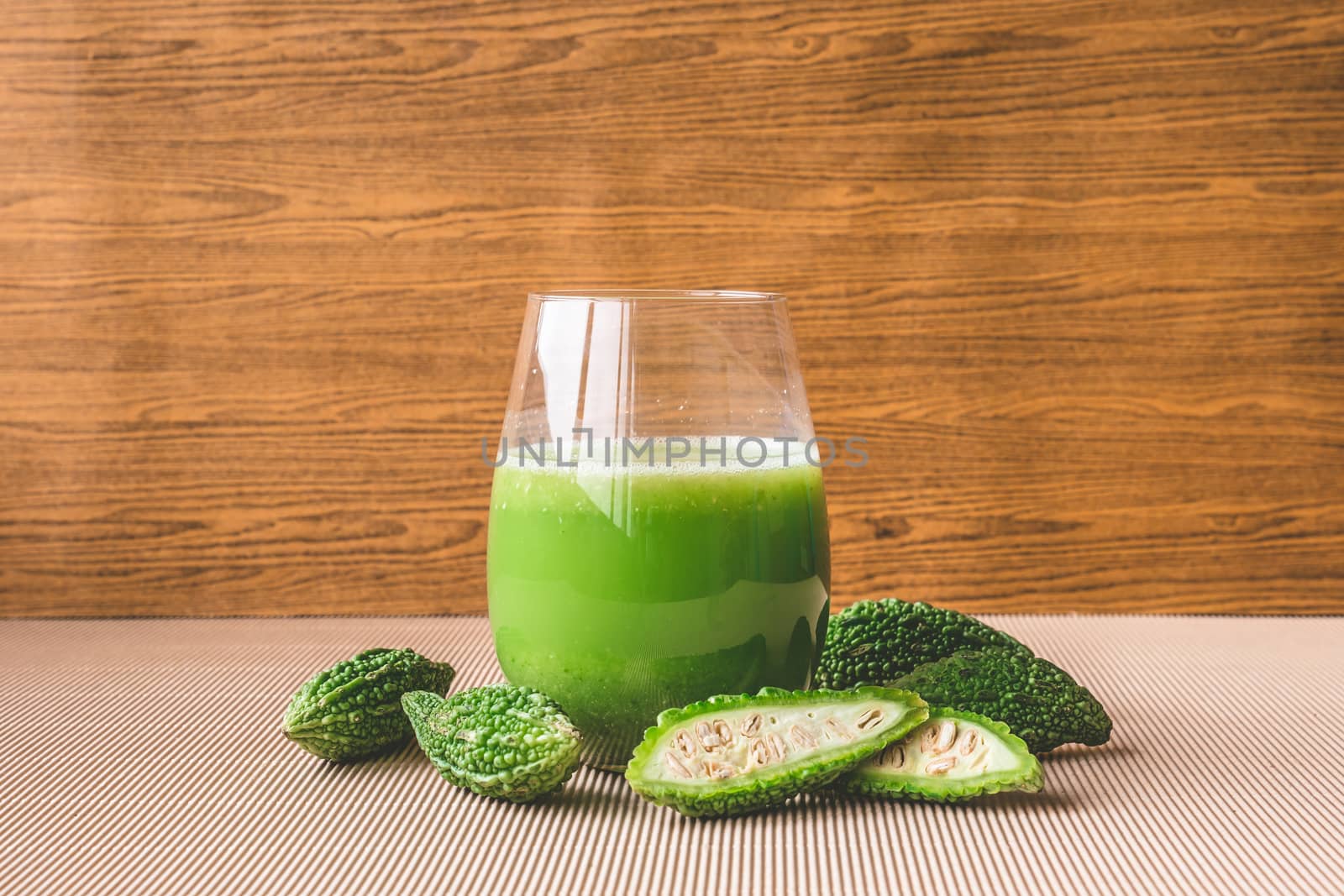 Herbal juice with bitter melon or bitter gourd on wooden background.