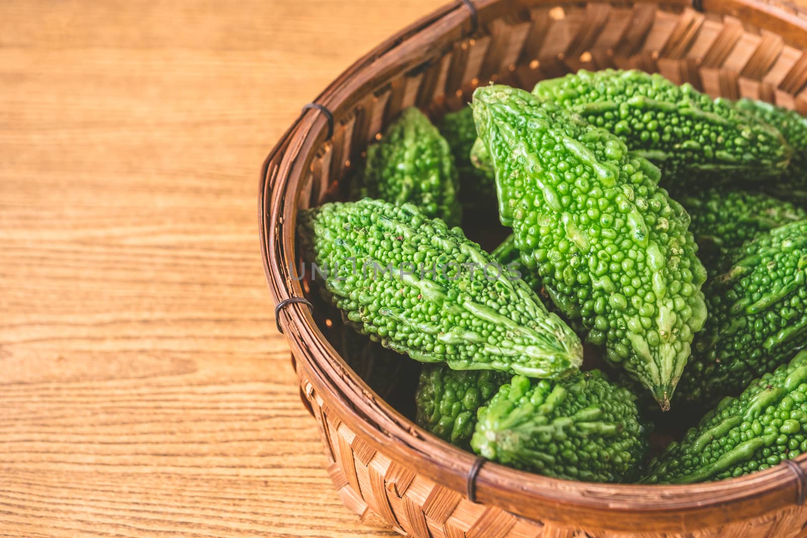 Bitter melon or bitter gourd in wooden basket. free space for text