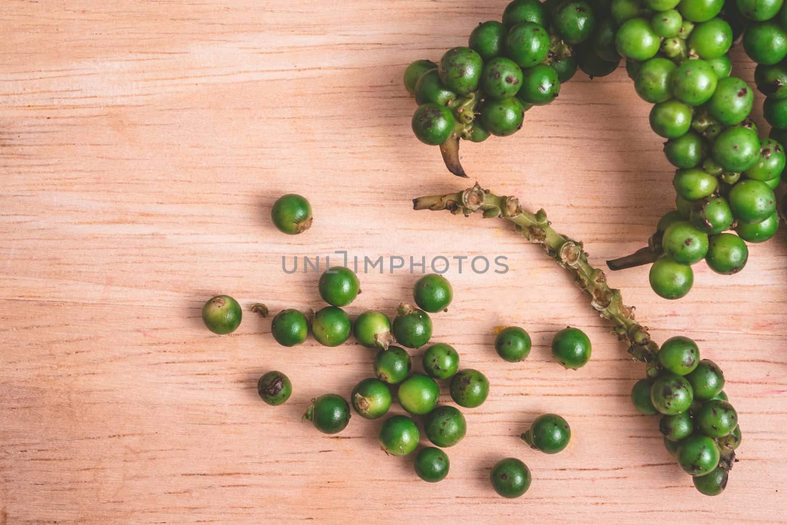 Green peppercorns on wooden background.