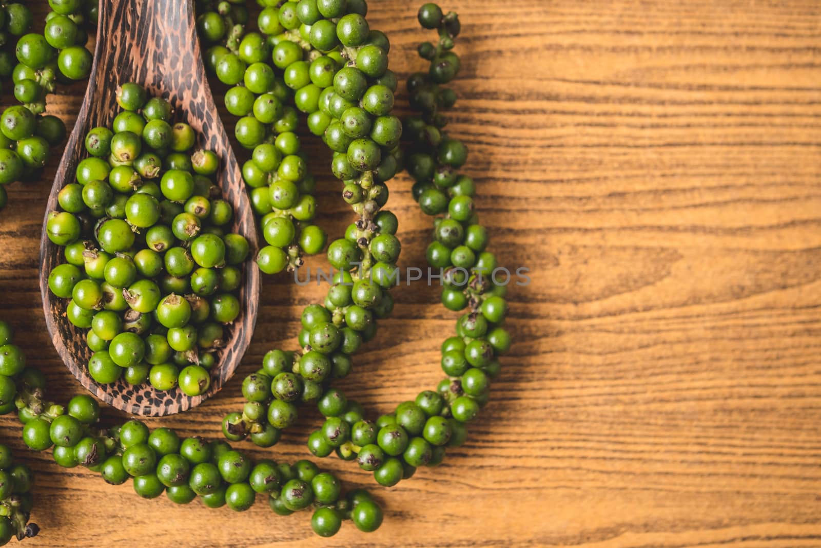 Green peppercorns on wooden background. Free space for text