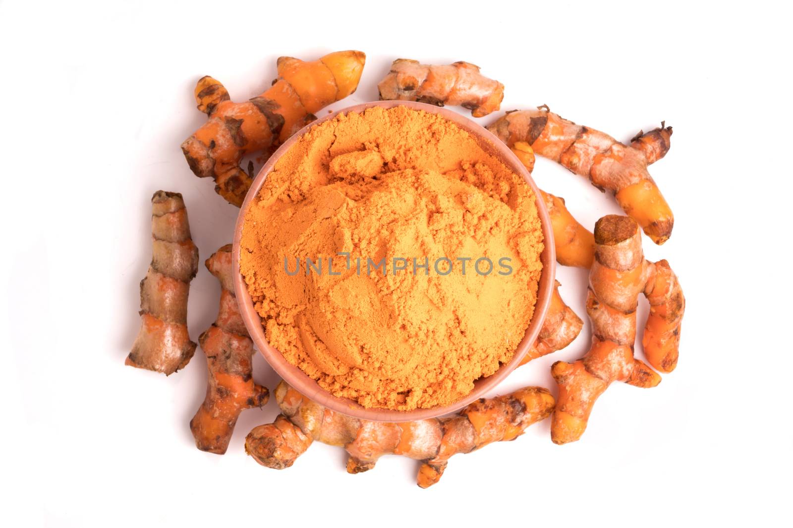 Turmeric roots with turmeric powder on white background.