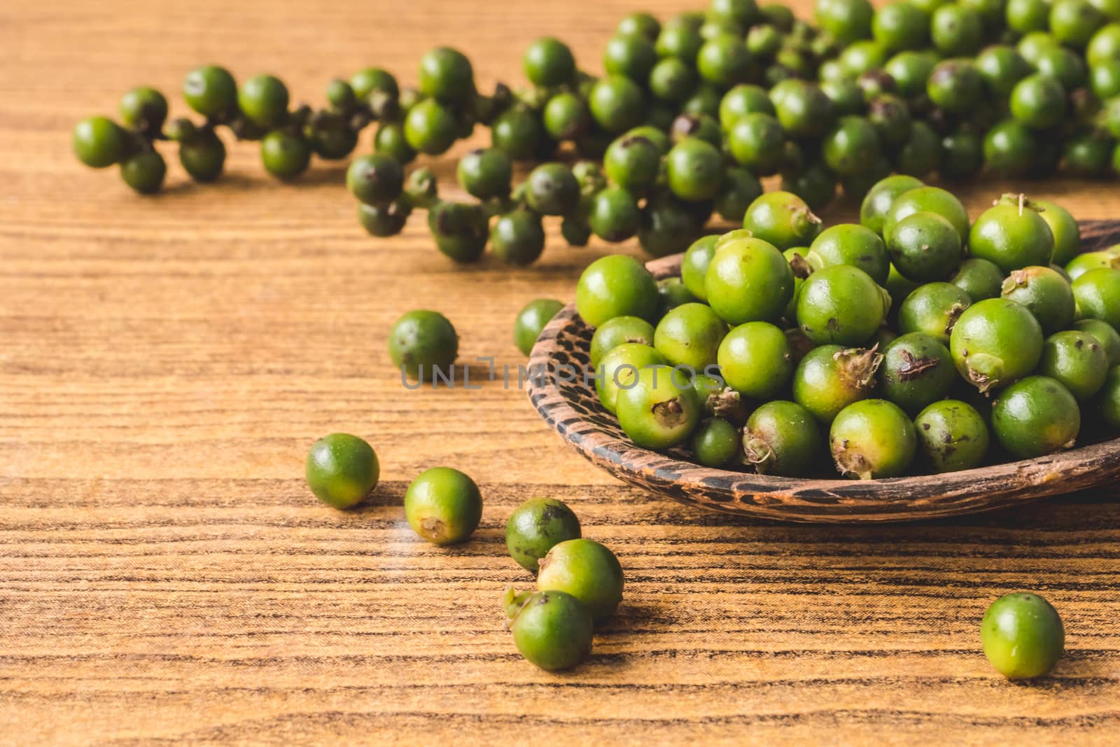 Green peppercorns on wooden background.