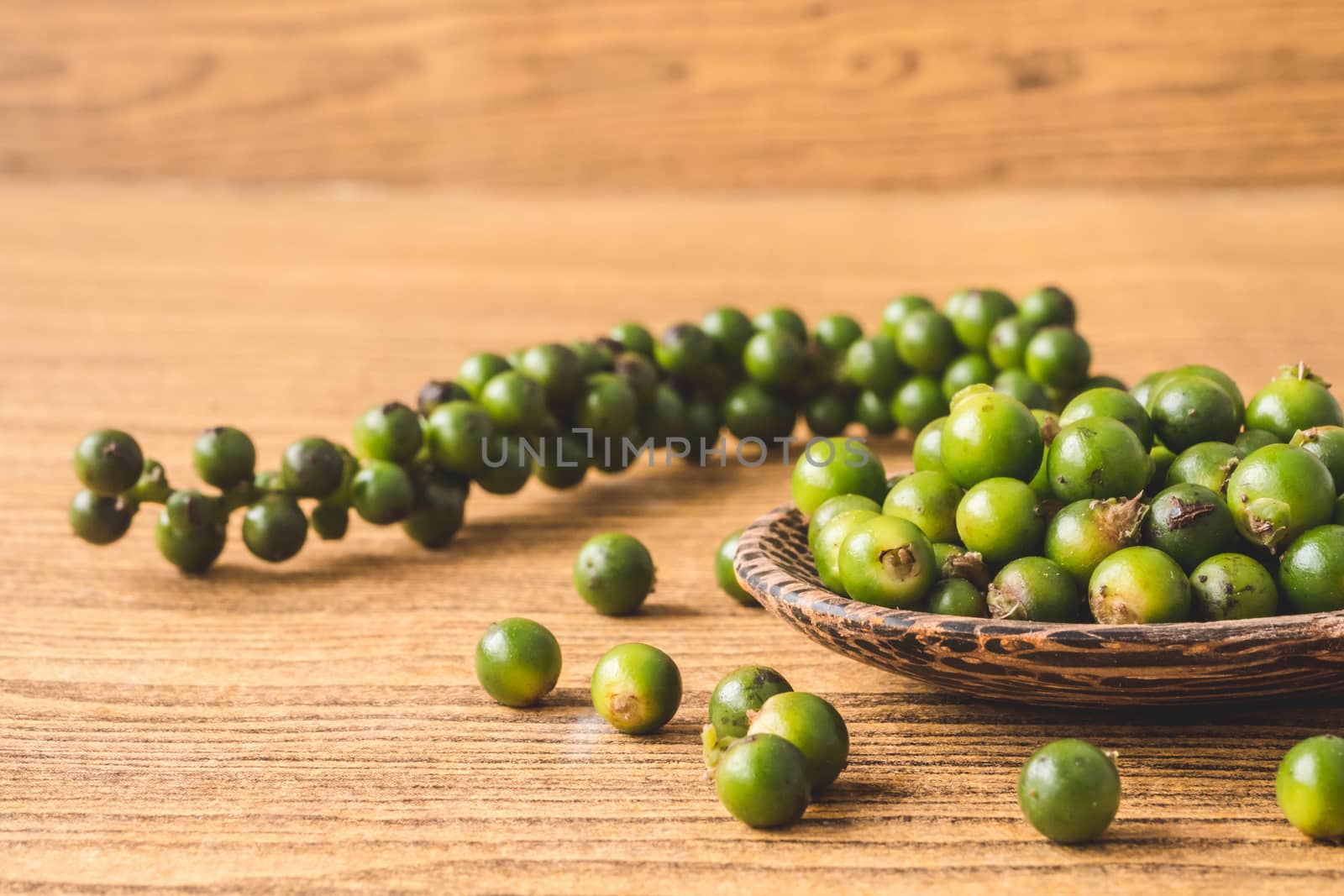 Green peppercorns on wooden background.