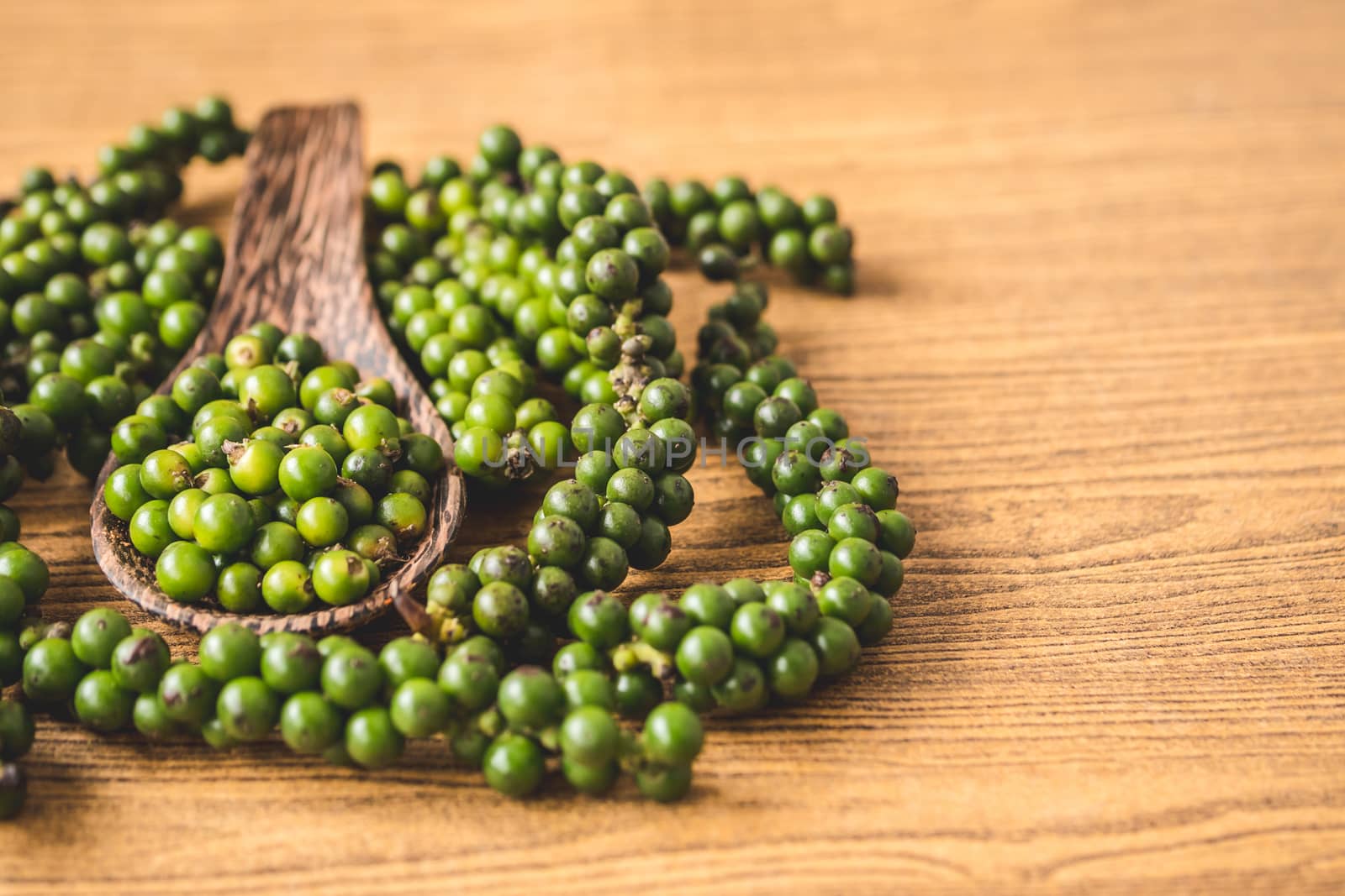 Green peppercorns on wooden background.