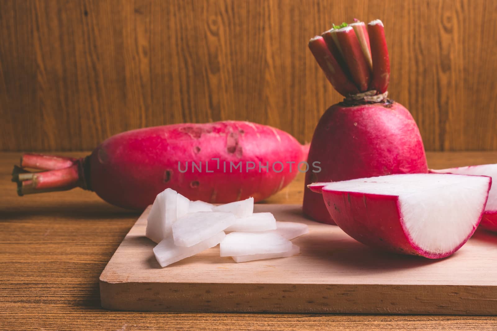 Fresh Pink Radishes on wooden cutting board over wooden table background by ronnarong