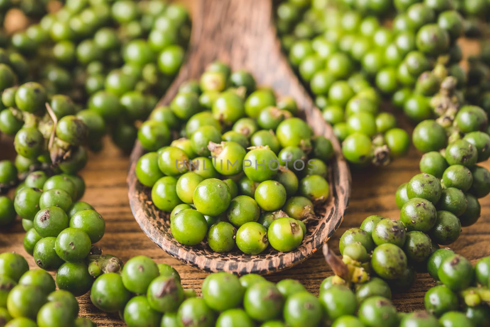 Green peppercorns on wooden background. by ronnarong