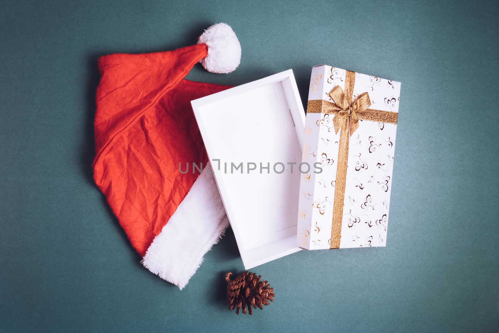 Top view of empty gift box with santa hat on green background.