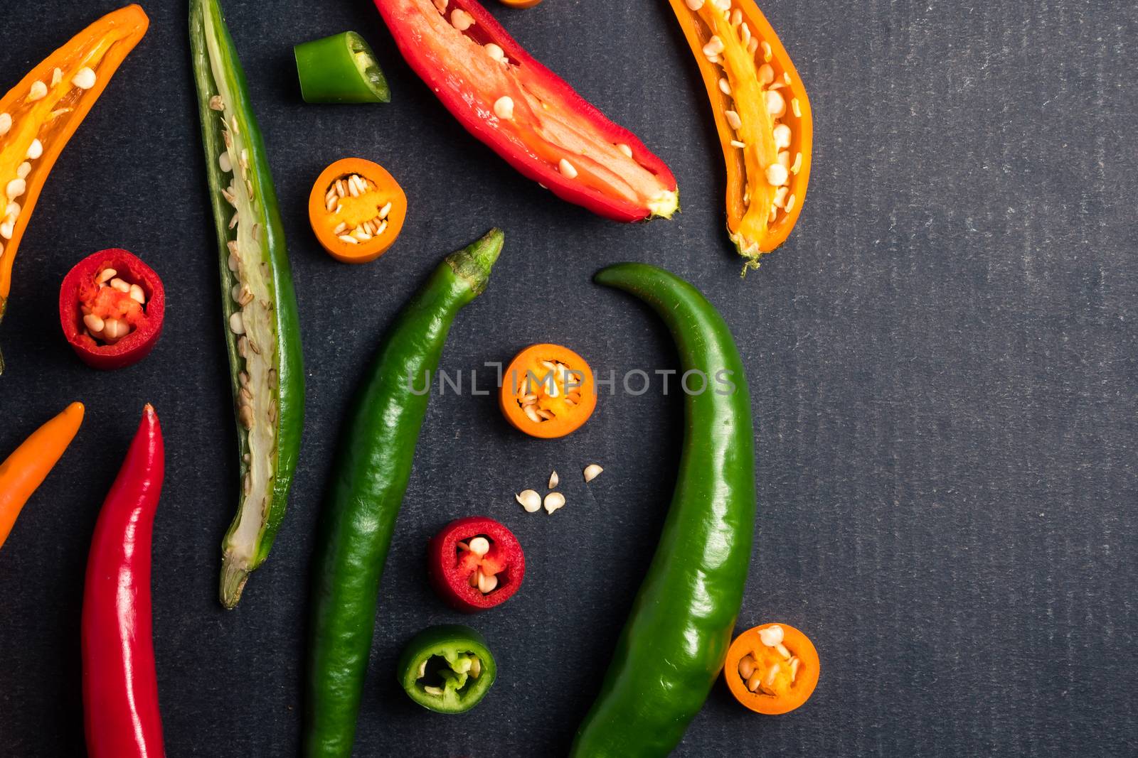 Colorful mix of chili pappers on black background.  by ronnarong