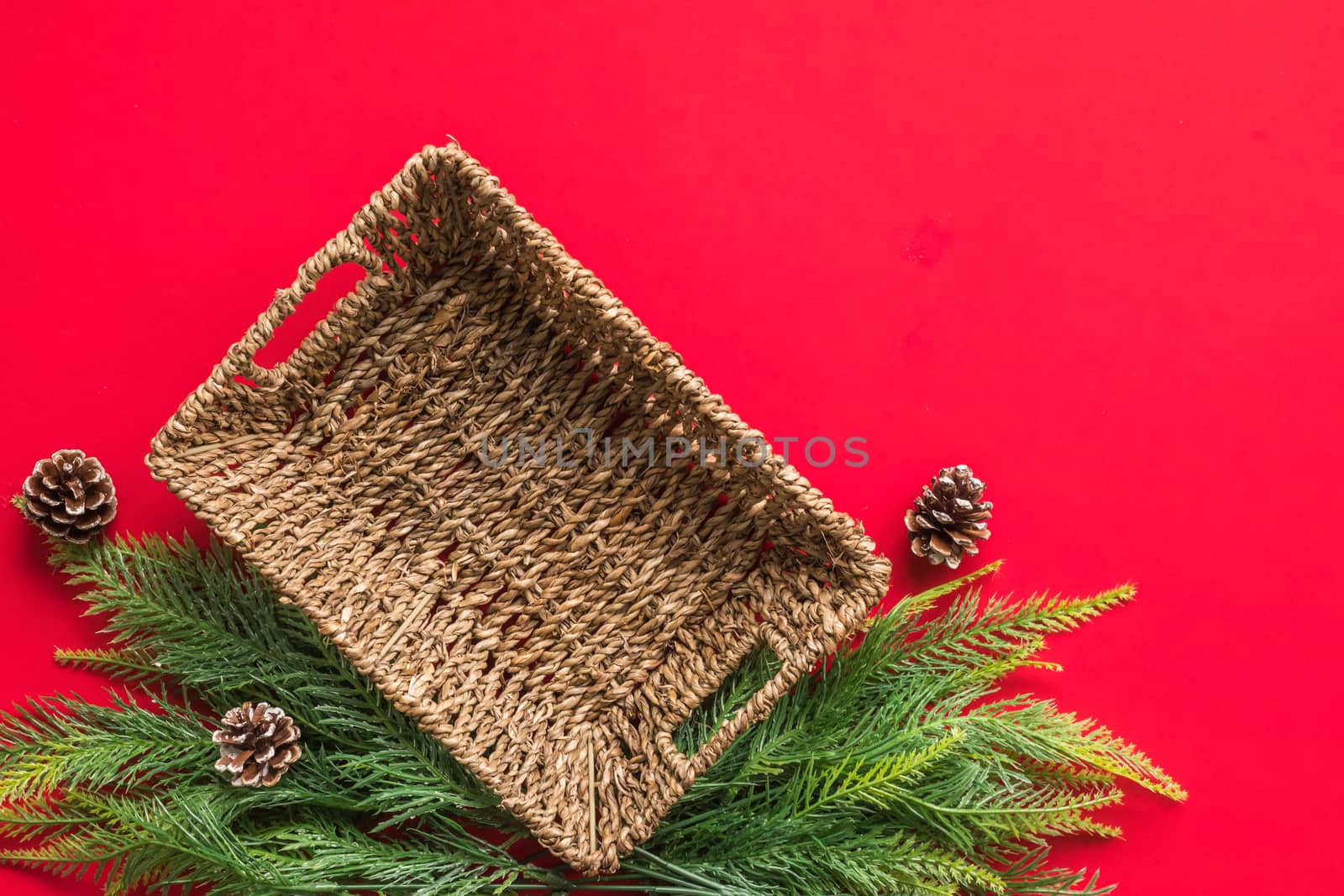 Empty basket with christmas tree branches on red background. Free space for text