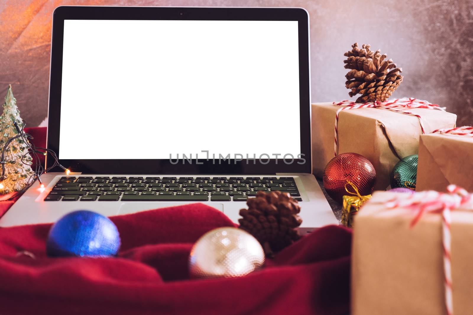 Laptop with white screen, gift boxes and christmas decoration on the table. by ronnarong