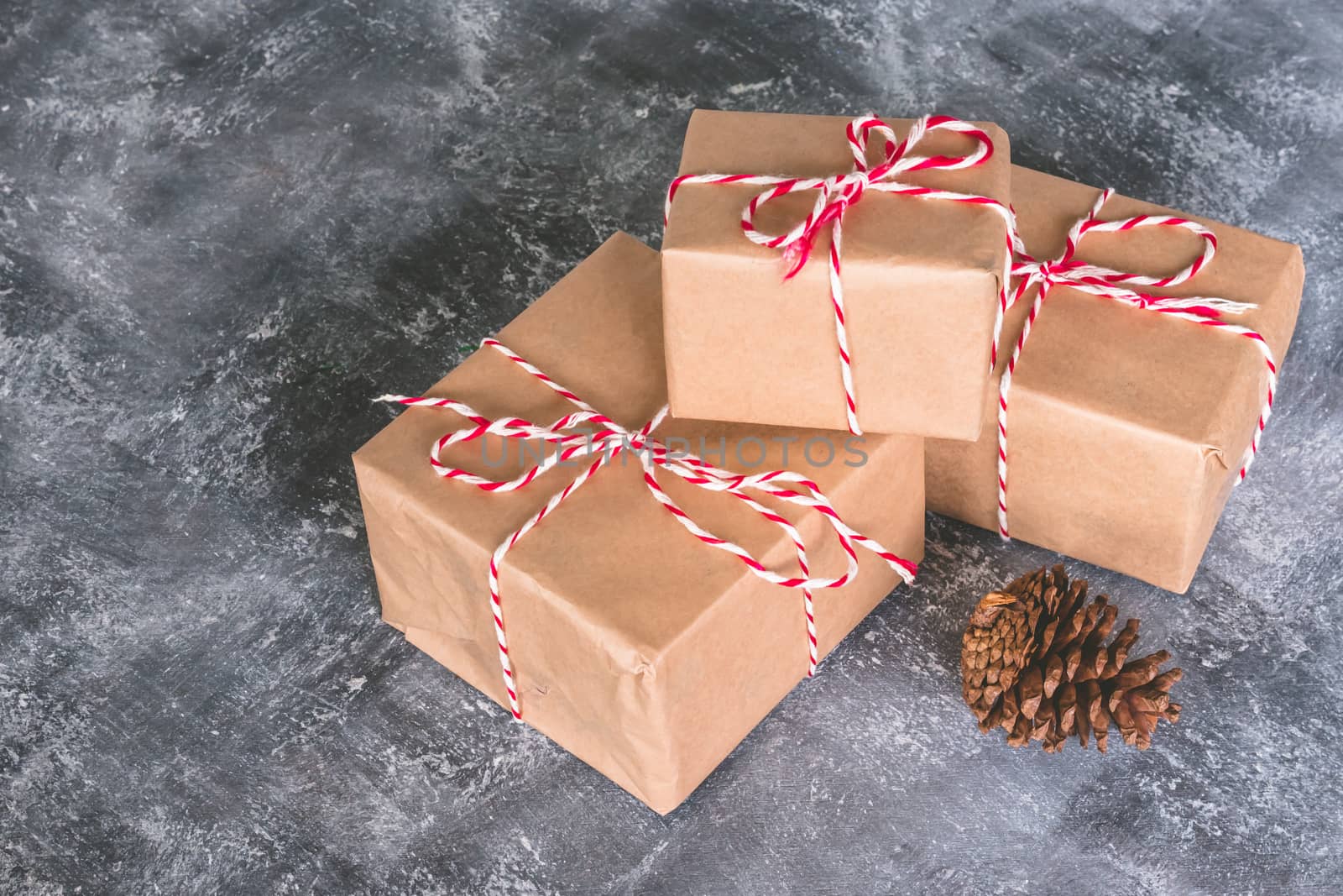 Gift packages wrapped in brown paper on gray grunge background.