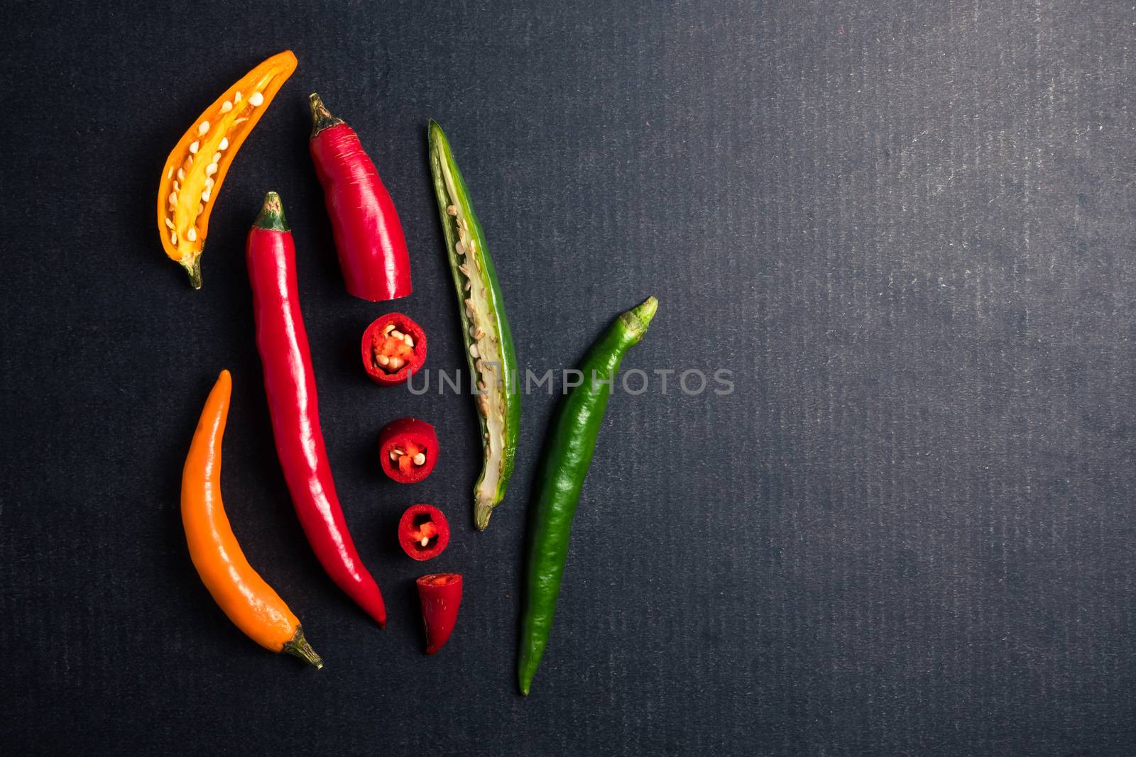 Colorful mix of chili pappers on black background. Free space for text