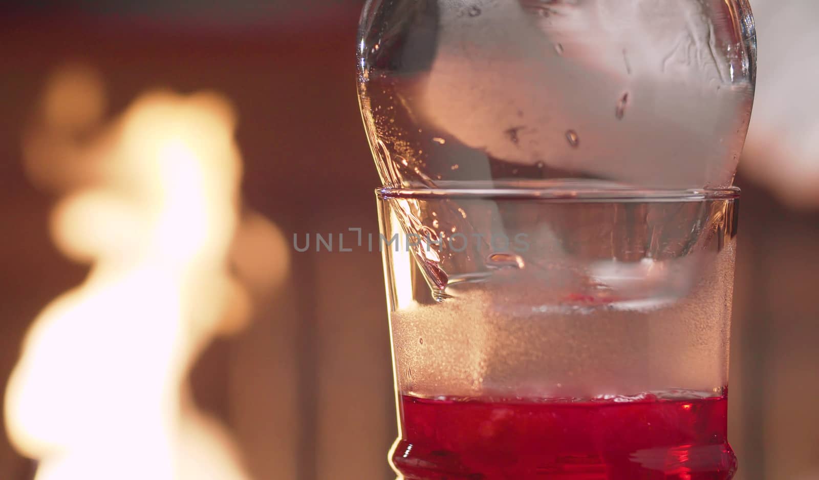 Cooking Raspberry Sambuca. Close up glass with hot sambuca covered with snifter on fire background