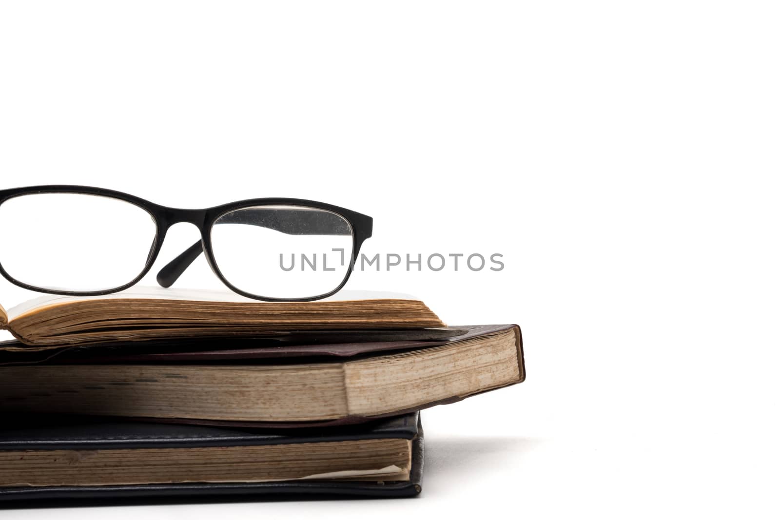 A stack of old books with eyeglasses on a white background. by ronnarong