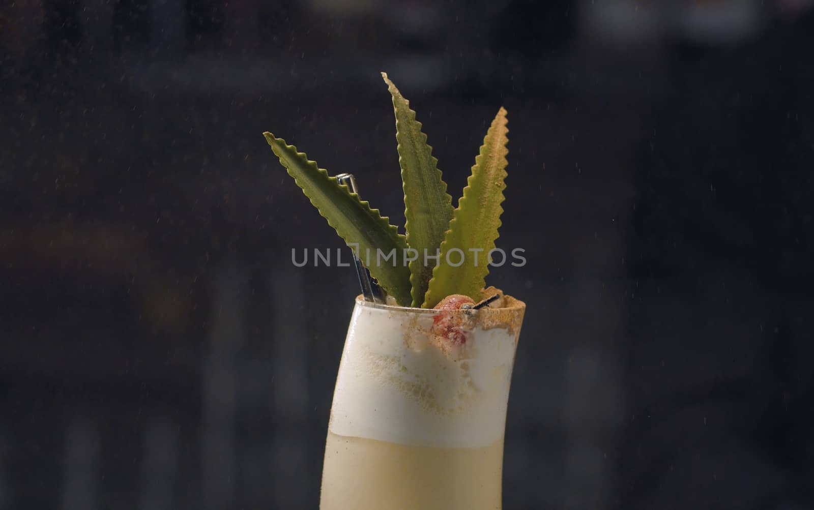 Close up pina colada cocktail sprinkled with burning cinnamon. Glass on the dark background. Bar drinks series.