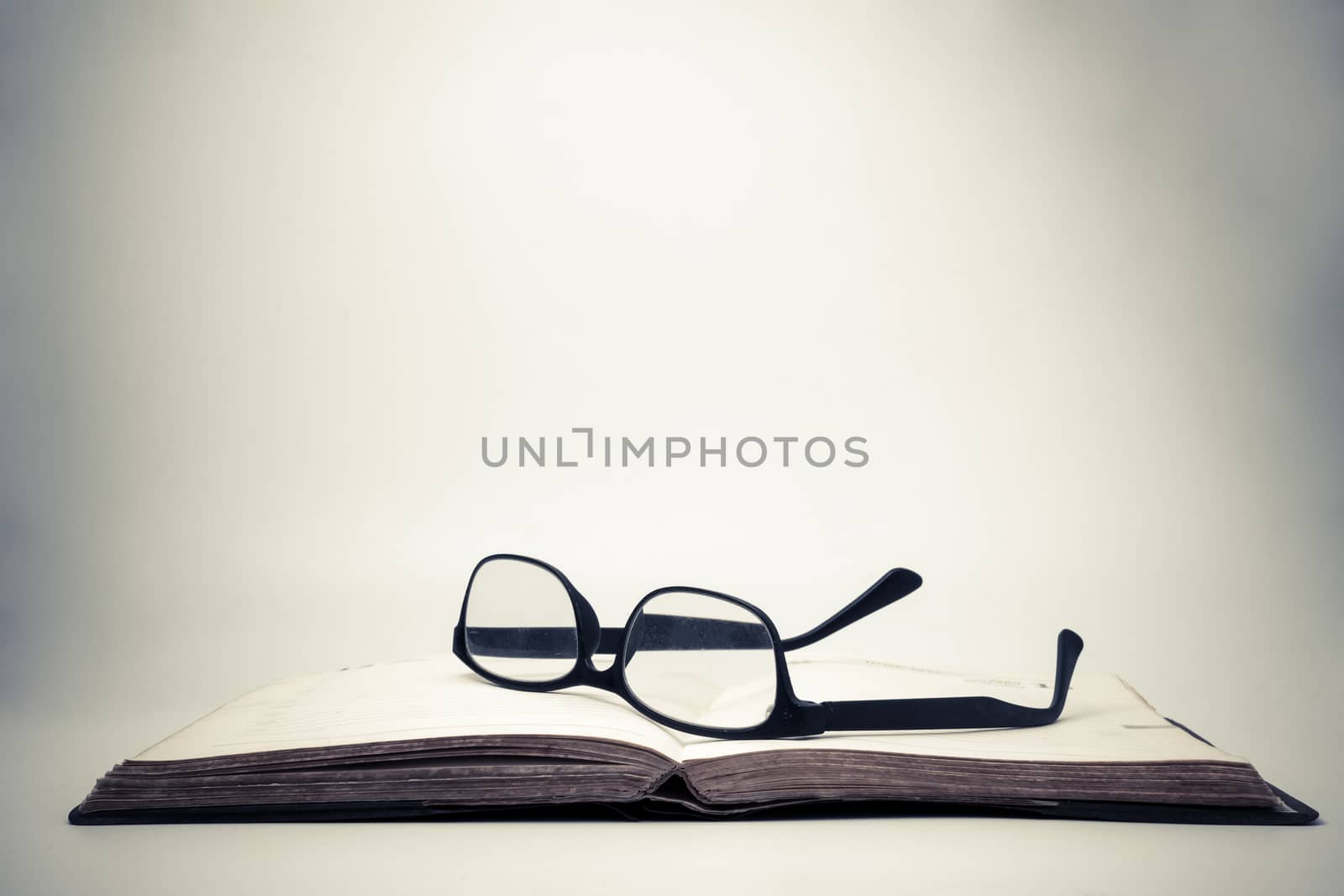 Eyeglasses on an open book with vintage background.