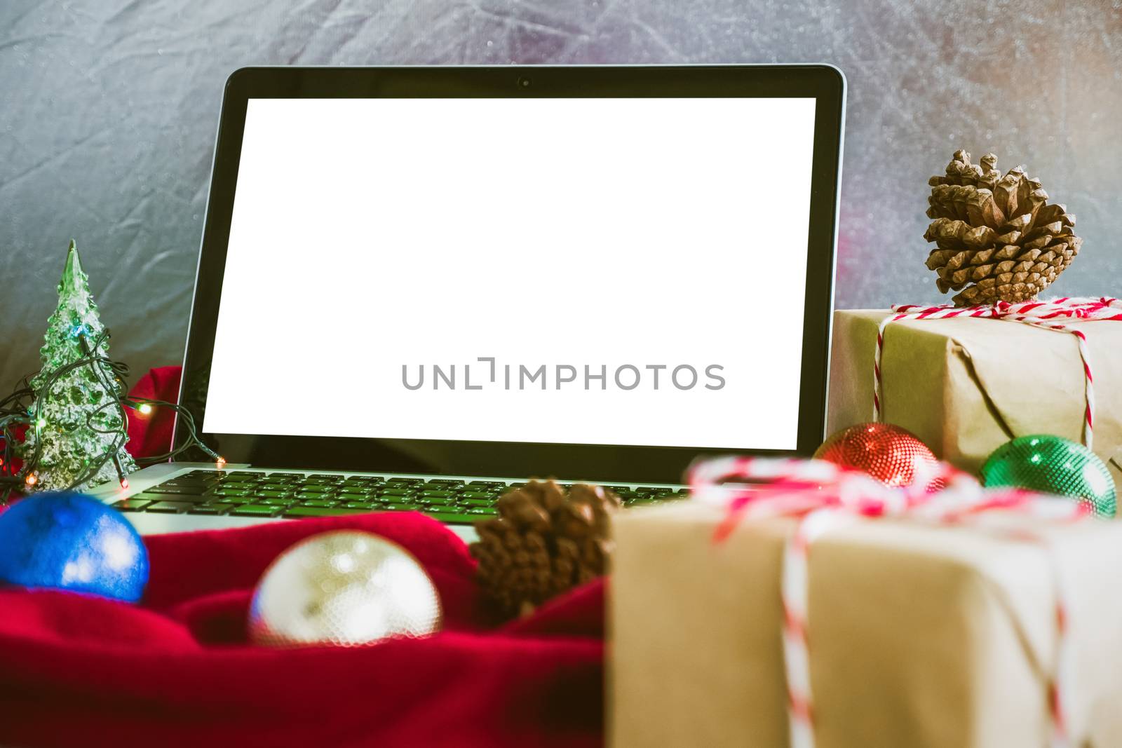 Laptop with white screen, gift boxes and christmas decoration on the table by ronnarong