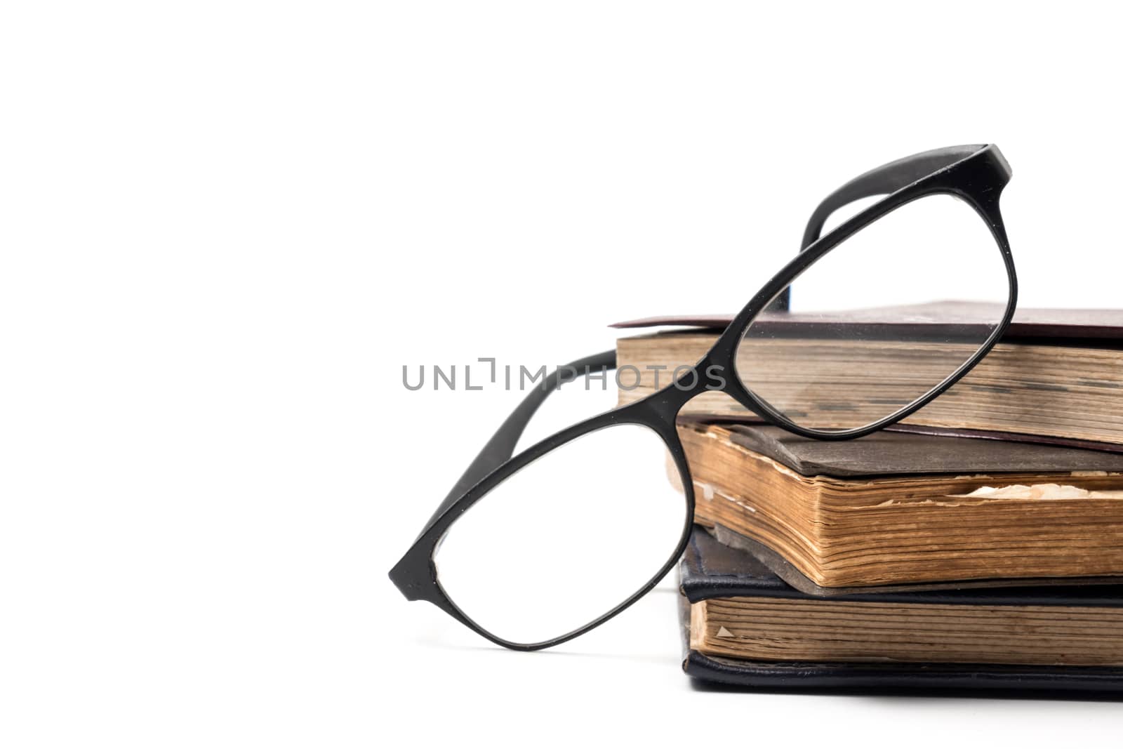A stack of old books with eyeglasses on a white background. Free space for text