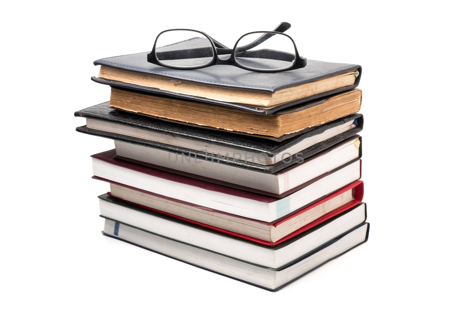 A stack of books with eyeglasses on a white background. by ronnarong