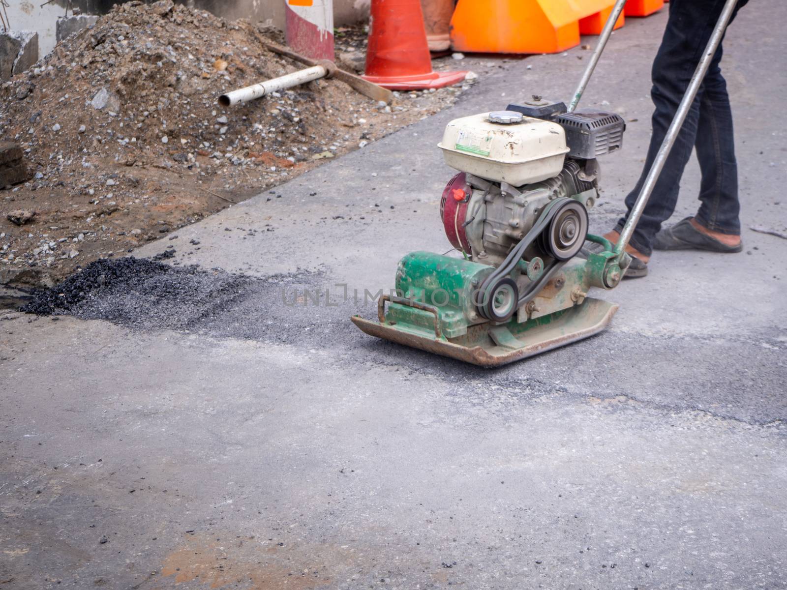 Worker use vibratory plate compactor compacting asphalt  by shutterbird