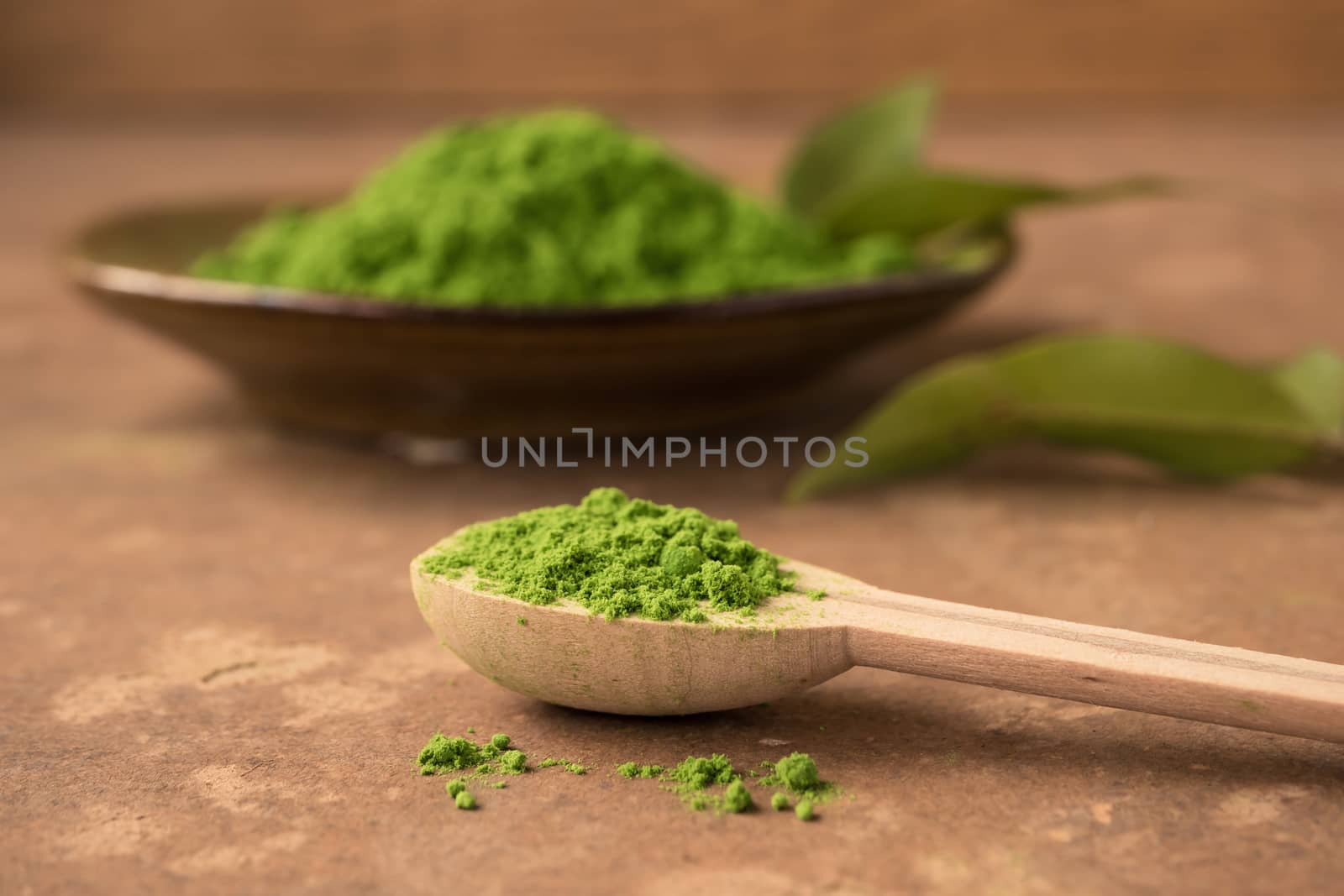 Close up of green tea powder in wooden spoon on the table.