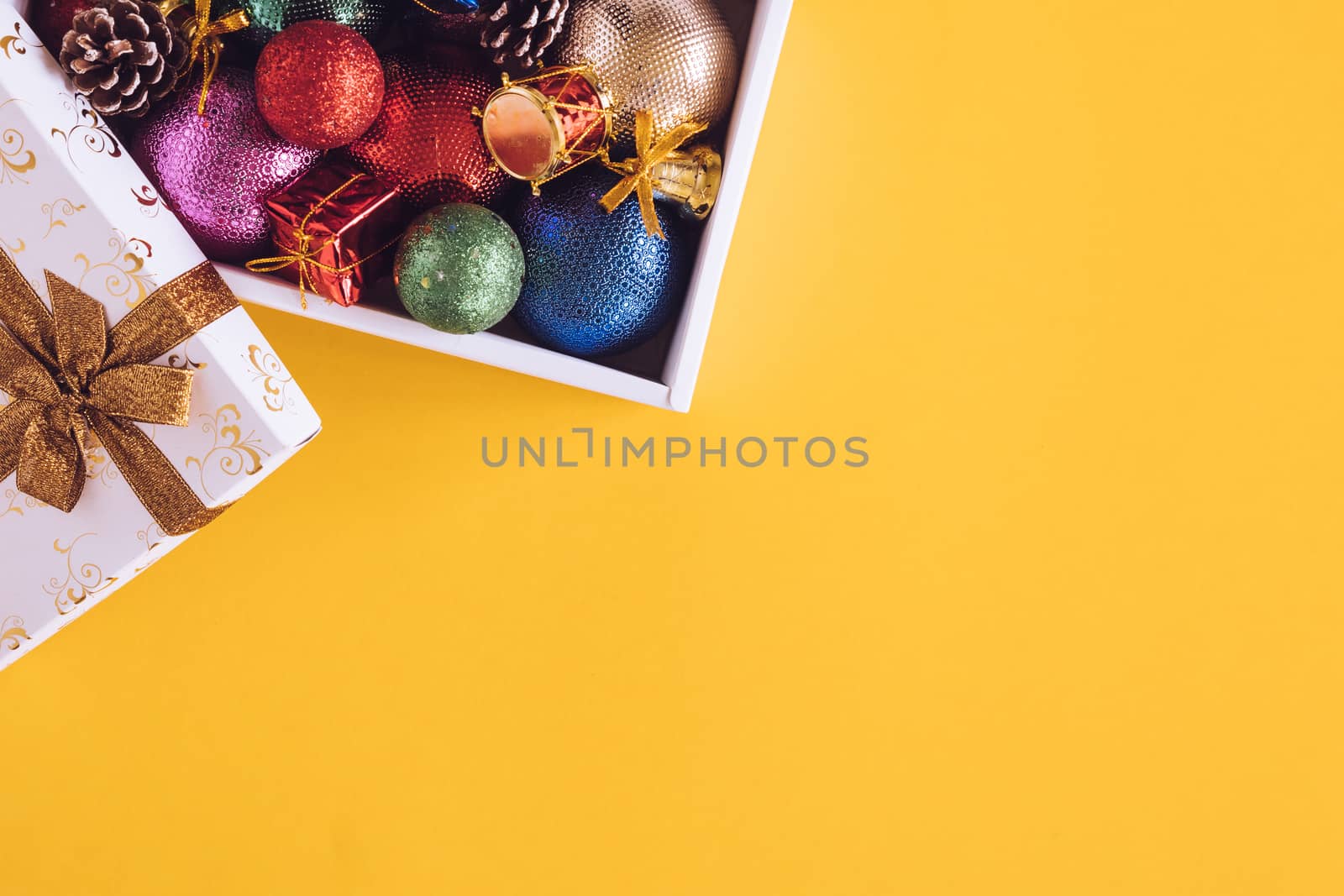 Christmas decorations in gift box on a yellow background. Free space for text