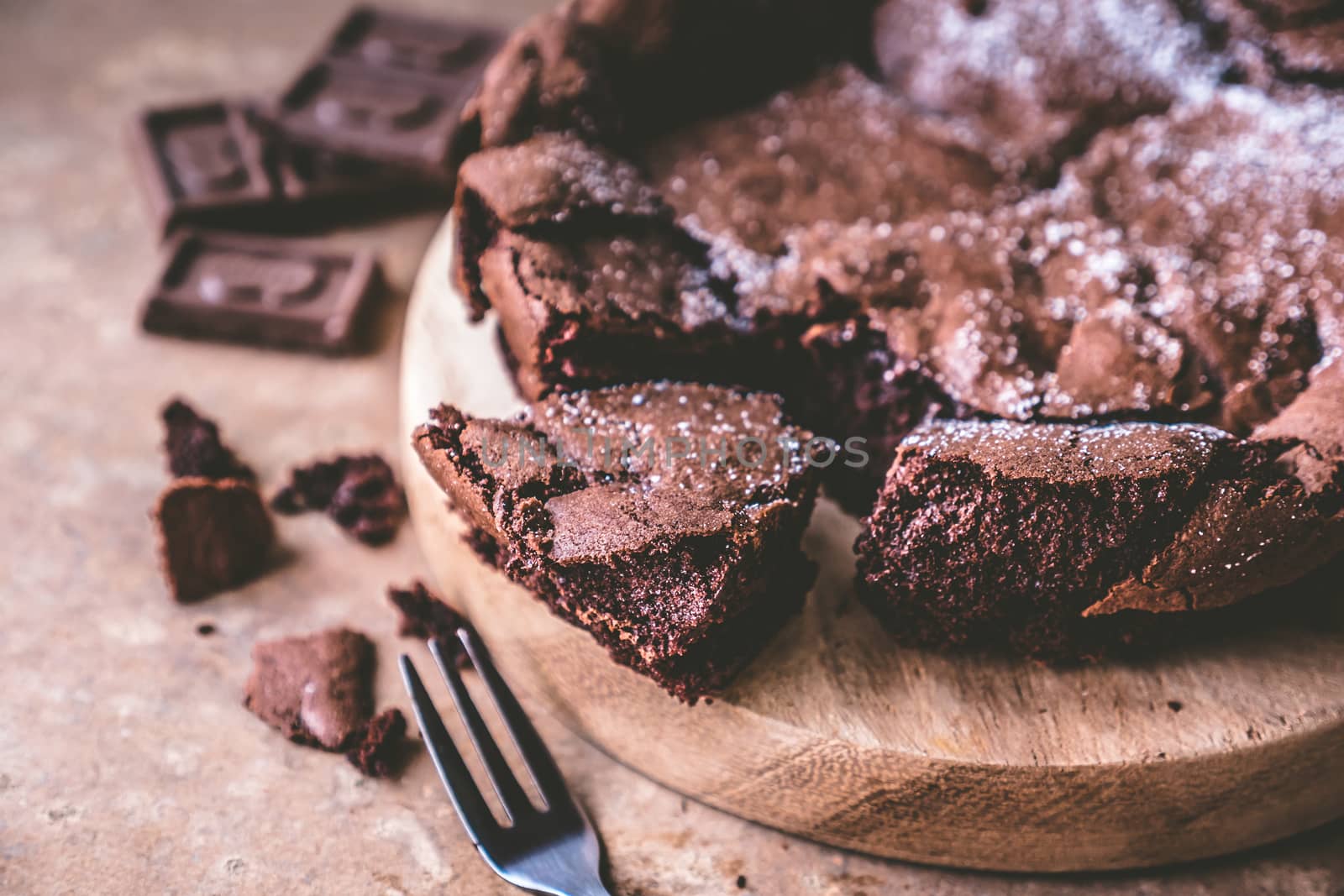 Close up of Chocolate cake on wooden tray with fork.