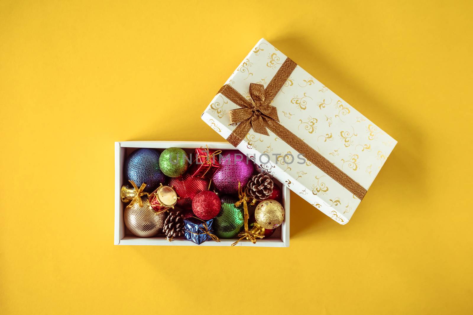 Christmas decorations in gift box on a yellow background.