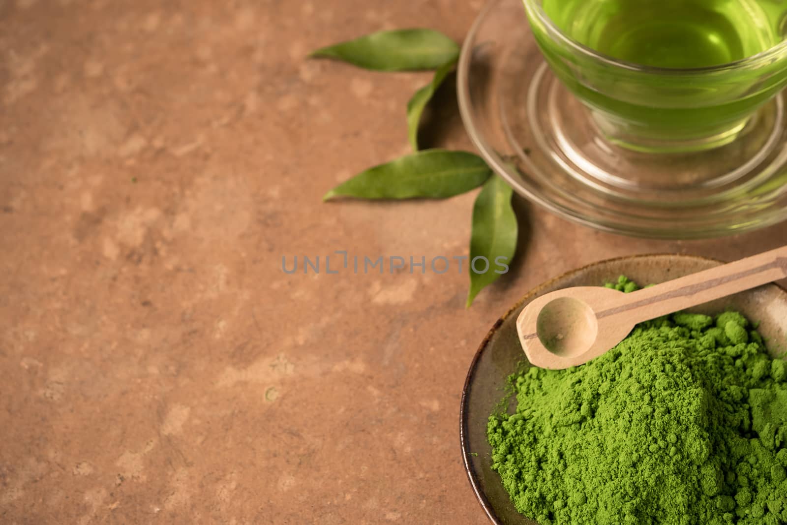 Close up of green tea powder with glass cup of hot tea on the table. Free space for text