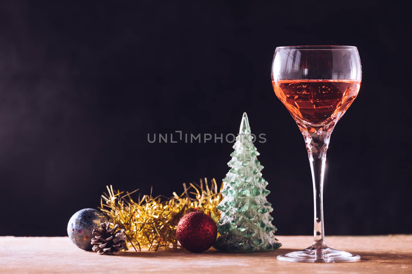 Glass of wine with Christmas decorations on the wooden table, black background, free space for text