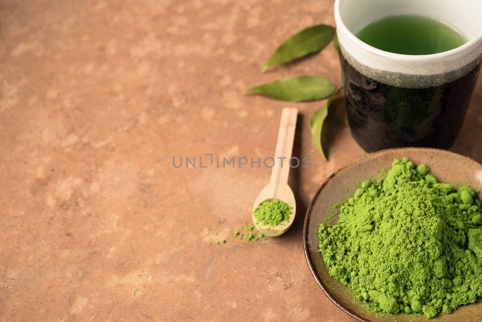 Top view of green tea powder with tea cup on the table. Free space for text