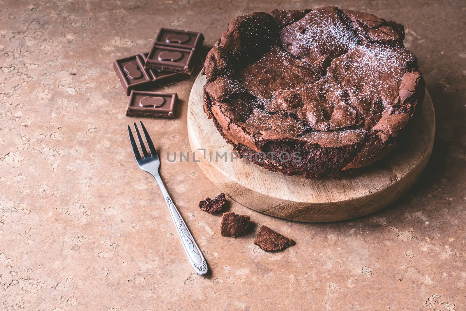 Chocolate cake on wooden tray with fork.