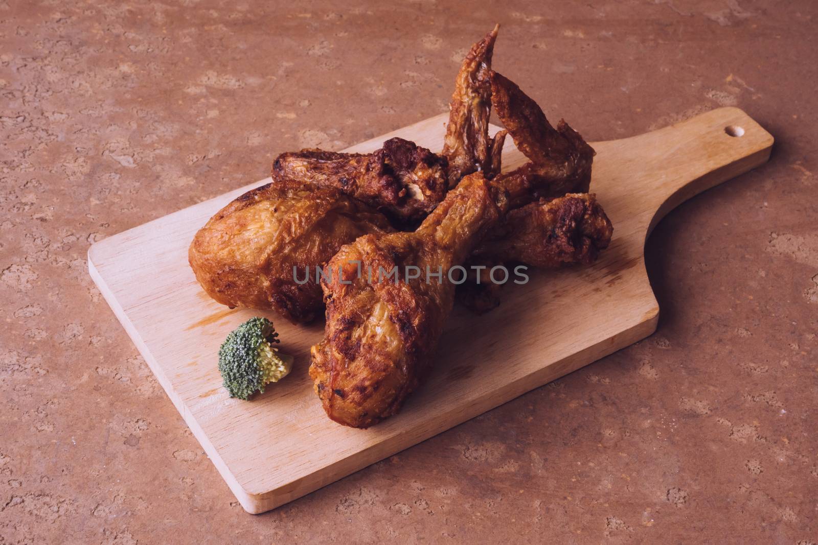 Fried chicken legs and wings on wooden tray.