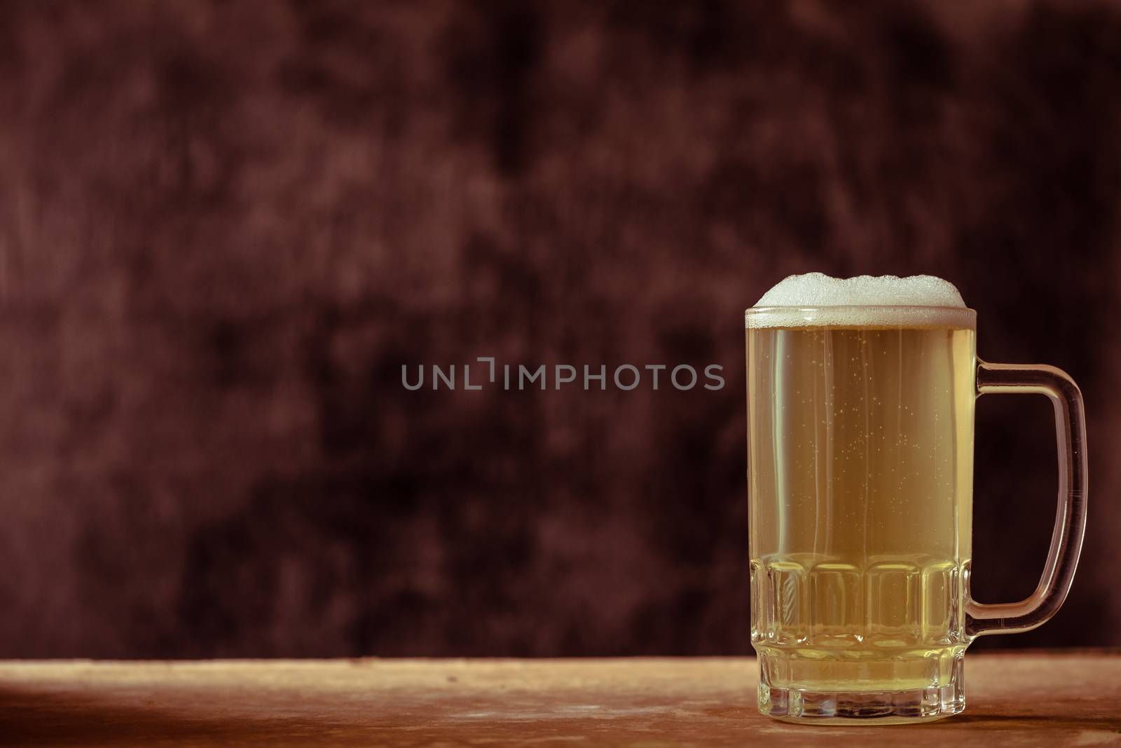 Mug of beer on the wooden table, dark background. vintage tone.  by ronnarong