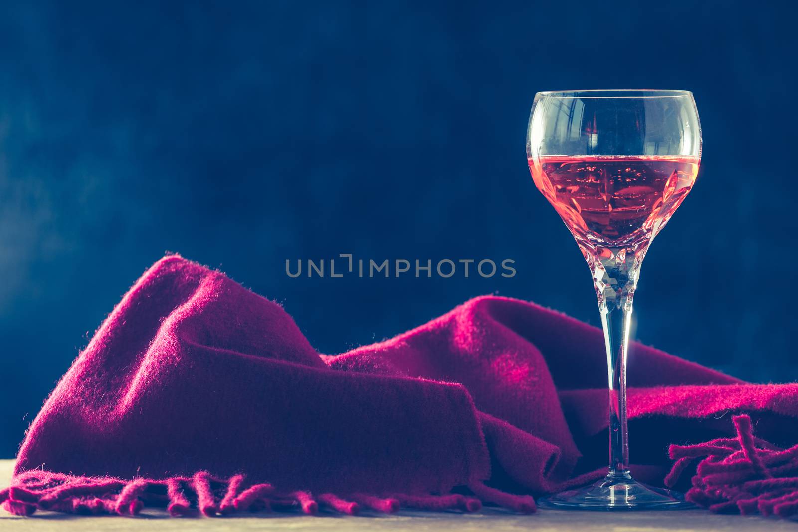 Glass of wine with red scarf on the table, black background, Free space for text, Vintage tone